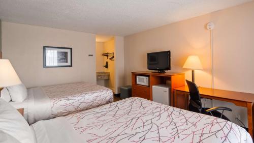 a hotel room with two beds and a desk with a television at Best Western Fredericksburg in Fredericksburg