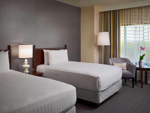 a hotel room with two beds and a chair at Sonesta Hotel Gwinnett Place Atlanta in Duluth