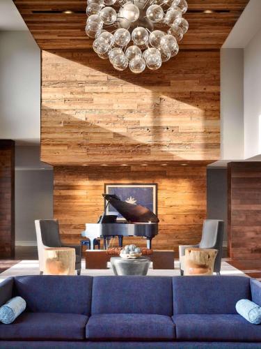 a living room with a blue couch and a piano at Sonesta Bee Cave Austin Hill Country in Bee Cave