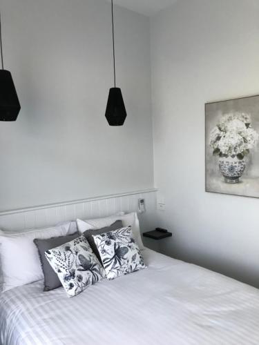 麦提福特Myrtleford Hotel的一张带枕头和花瓶的白色床