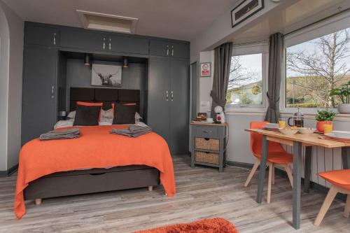 a bedroom with a bed with an orange blanket and a table at Soay@Knock View Apartments, Sleat, Isle of Skye in Teangue
