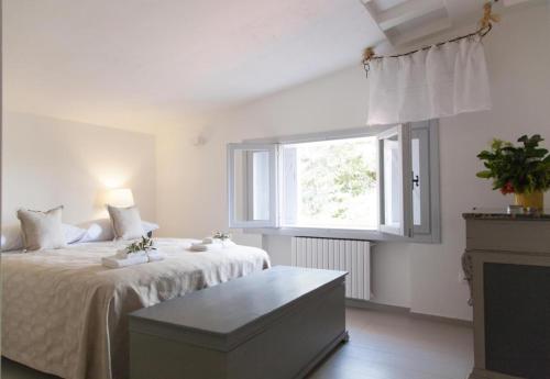 a white bedroom with a bed and a window at Villa con piscina mozzafiato, giardino e barbecue in Polignano a Mare