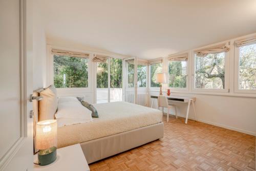 a bedroom with a bed and a desk and windows at Villa dei Lauri - villa vista lago con piscina in Salò