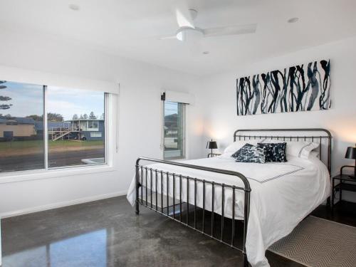 Un dormitorio blanco con una cama y una ventana. en Catalina, en Culburra Beach