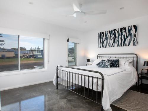a white bedroom with a bed and a window at Catalina in Culburra Beach