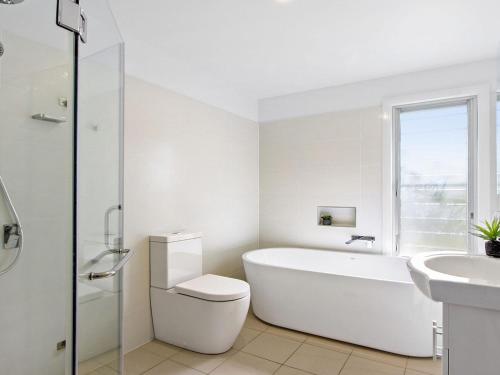 Un baño blanco con bañera, inodoro y lavabo. en Catalina, en Culburra Beach