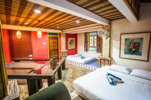 a room with two beds and a glass table at Lost Paradise Resort in Batu Ferringhi