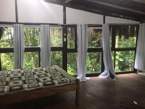 a bedroom with large windows and a bed in a room at Bosque dos Esquilos in Abraão