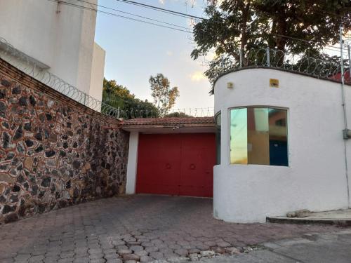 a garage with a red door next to a building at Rincón de Luz Cuernavaca in Cuernavaca