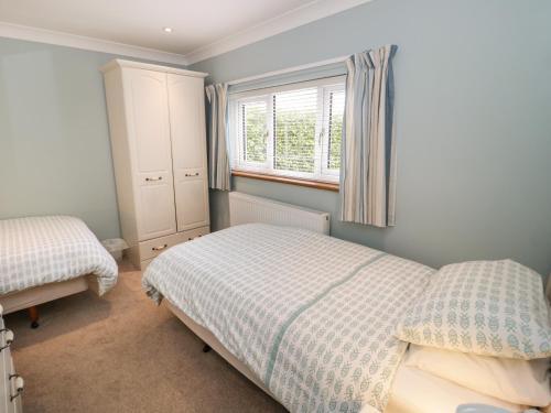 a bedroom with two beds and a window at Bryn Y Don Cottage in Benllech