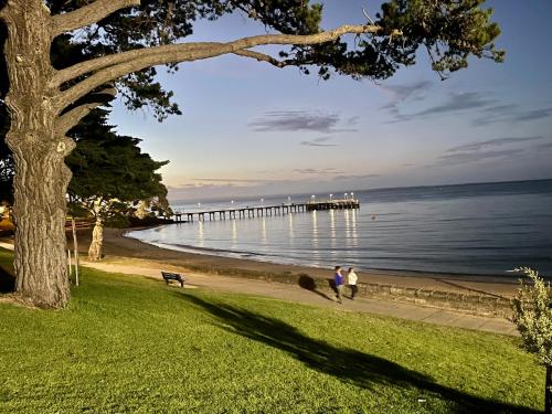 two people walking on the beach near a pier at C-Scape water front apartment in Cowes