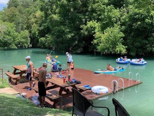 
people sitting on a picnic table in the water at Geronimo Creek Retreat Getaway Cabin #3 in Seguin
