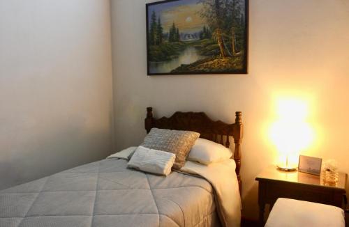 a bedroom with a bed and a painting on the wall at Casa de hospedaje Vivaio in Paipa