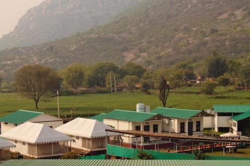 a group of buildings with green roofs and a mountain at Shivir Aranya - Wilderness Resort in Alwar
