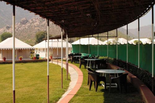 a row of tables with white umbrellas in a field at Shivir Aranya - Wilderness Resort in Alwar