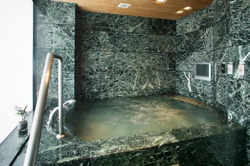 a bathroom with a large bath tub in a black stone wall at Honjin Hiranoya Kachoan in Takayama