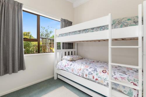 een slaapkamer met een stapelbed en een raam bij Taranui Escape - Mangawhai Heads Holiday Home in Mangawhai