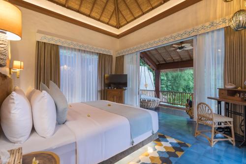 a bedroom with a large white bed and a balcony at Arkana Village Canggu by Nagisa Bali in Canggu