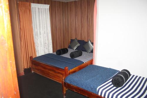 a bedroom with two beds with blue and white sheets at Bezel Bungalow Nuwara Eliya in Nuwara Eliya