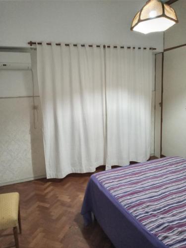 1 dormitorio con cama y cortina blanca en Bienvenido avenida corrientes en Buenos Aires