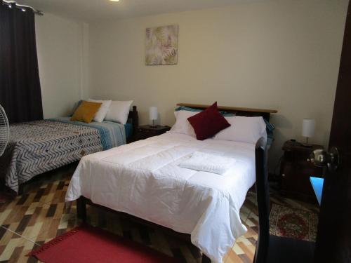1 dormitorio con 1 cama con sábanas blancas y almohadas rojas en jazmines point, en Lima