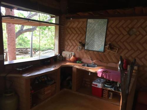 eine kleine Küche mit einem Waschbecken und einem Fenster in der Unterkunft Chalé na Chapada, com acesso ao Rio São Miguel in Sao Jorge