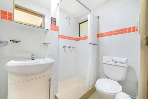 a white bathroom with a toilet and a sink at Hotel de la Salle in Bogotá