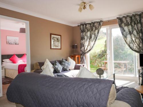 a bedroom with a bed and a couch and a window at Watergate Bay in Liskeard