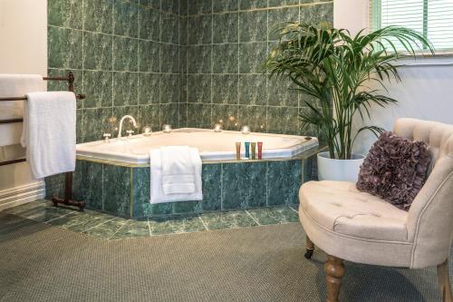 y baño con bañera y silla. en Moulton Park Estate - Cottages, en Sassafras