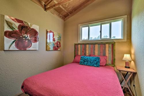 a bedroom with a pink bed and a window at View House in Laupahoehoe with Patio and Ocean Views! in Papaaloa