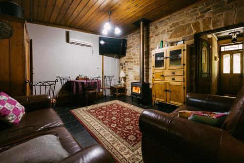 a living room with leather furniture and a stone wall at Mintaro Hideaway in Mintaro