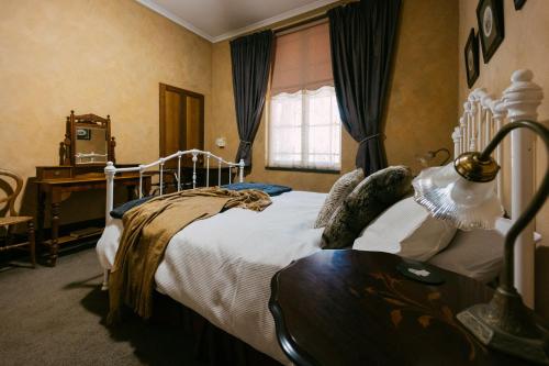 een slaapkamer met een bed, een tafel en een raam bij Mintaro Hideaway in Mintaro