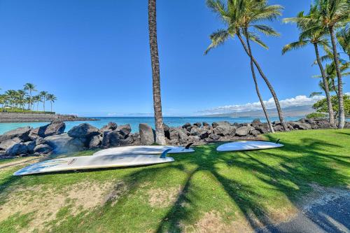 a surfboard laying on the grass next to palm trees at Waimea Condo Less Than 1 Mile from Mauna Lani Beach Club! in Waikoloa