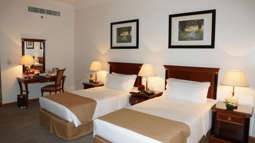 a hotel room with two beds and a desk at Executives Hotel - Olaya in Riyadh