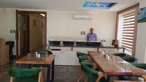 a man standing in a restaurant with tables and chairs at Hotel Dream Inn in Rishīkesh