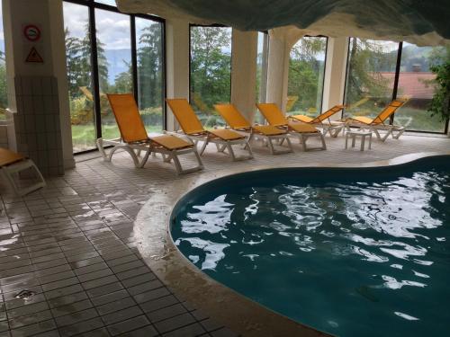 a swimming pool with orange chairs and a group at Le Bristol - Villars Bristol Apartments in Villars-sur-Ollon