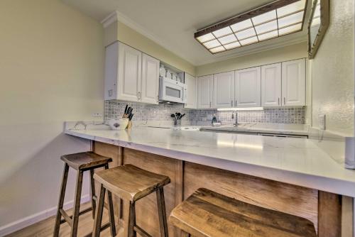 a kitchen with white cabinets and two stools at Kihei Retreat with Kamaole Sands Resort Amenities! in Wailea
