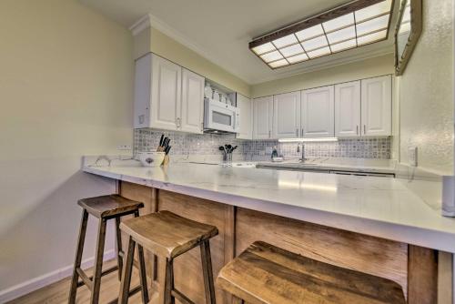 a kitchen with white cabinets and two stools at Ocean View Kihei Retreat with Resort Amenities! in Wailea