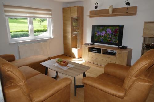 sala de estar con sillas de cuero y TV de pantalla plana en 4 Sterne Ferienwohnung Sommerberg inklusive Gästekarte en Rohrbach