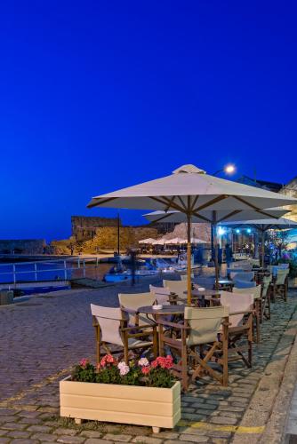 a row of tables and chairs with an umbrella at Porto Veneziano Hotel in Chania Town