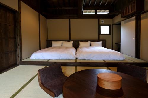 a room with two beds and a table in it at kominka neri（古民家煉り） in Miyawaka
