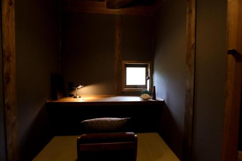 a dark room with a chair and a window at kominka neri（古民家煉り） in Miyawaka