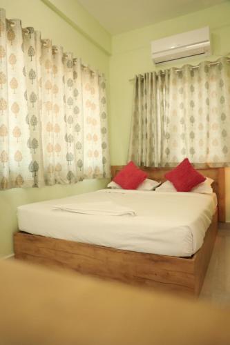 a bed with two red pillows in a bedroom at Sai Inn Mysore in Mysore