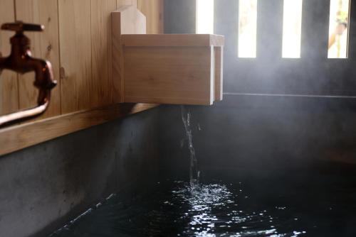 a bath tub with water coming out of a faucet at kominka neri（古民家煉り） in Miyawaka