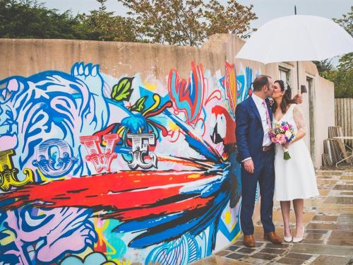 a bride and groom kissing under an umbrella at Lower Barns Guest House in Mevagissey