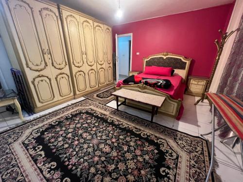 - une chambre avec un lit et un mur rouge dans l'établissement Family Apartment in Nasr City, au Caire