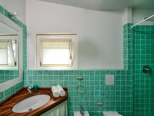 a green tiled bathroom with a sink and a window at Case Li Conchi Sardegna in Castiadas
