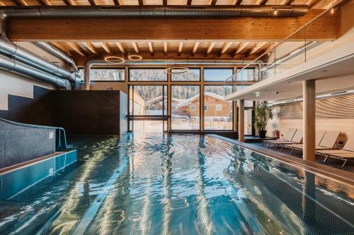 a swimming pool in a building with a large window at Hofgut Apartment & Lifestyle Resort Wagrain in Wagrain