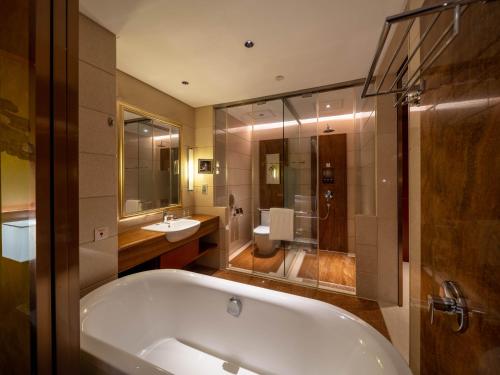 a bathroom with a tub and a toilet and a sink at Marco Polo Jin Jiang in Jinjiang
