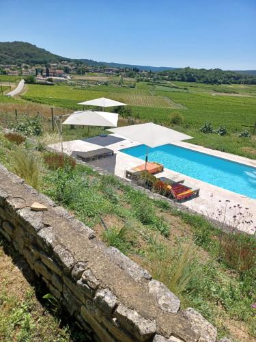 - une piscine avec des parasols et des chaises à côté d'un mur dans l'établissement Mas Les Escourtades Chambres d'hôtes, à Cornillon